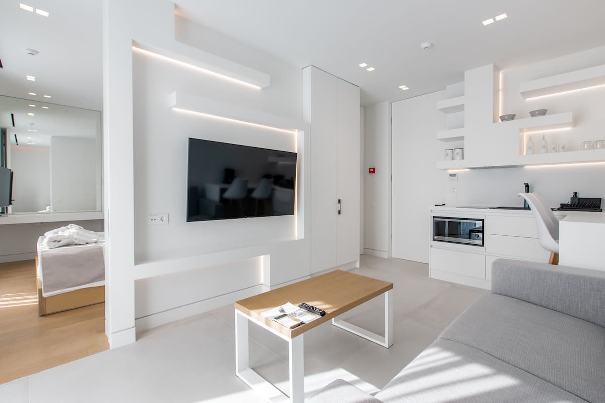 Un salon moderne et minimaliste, doté d’un téléviseur à écran plat, d’une table basse en bois et d’un canapé gris.
