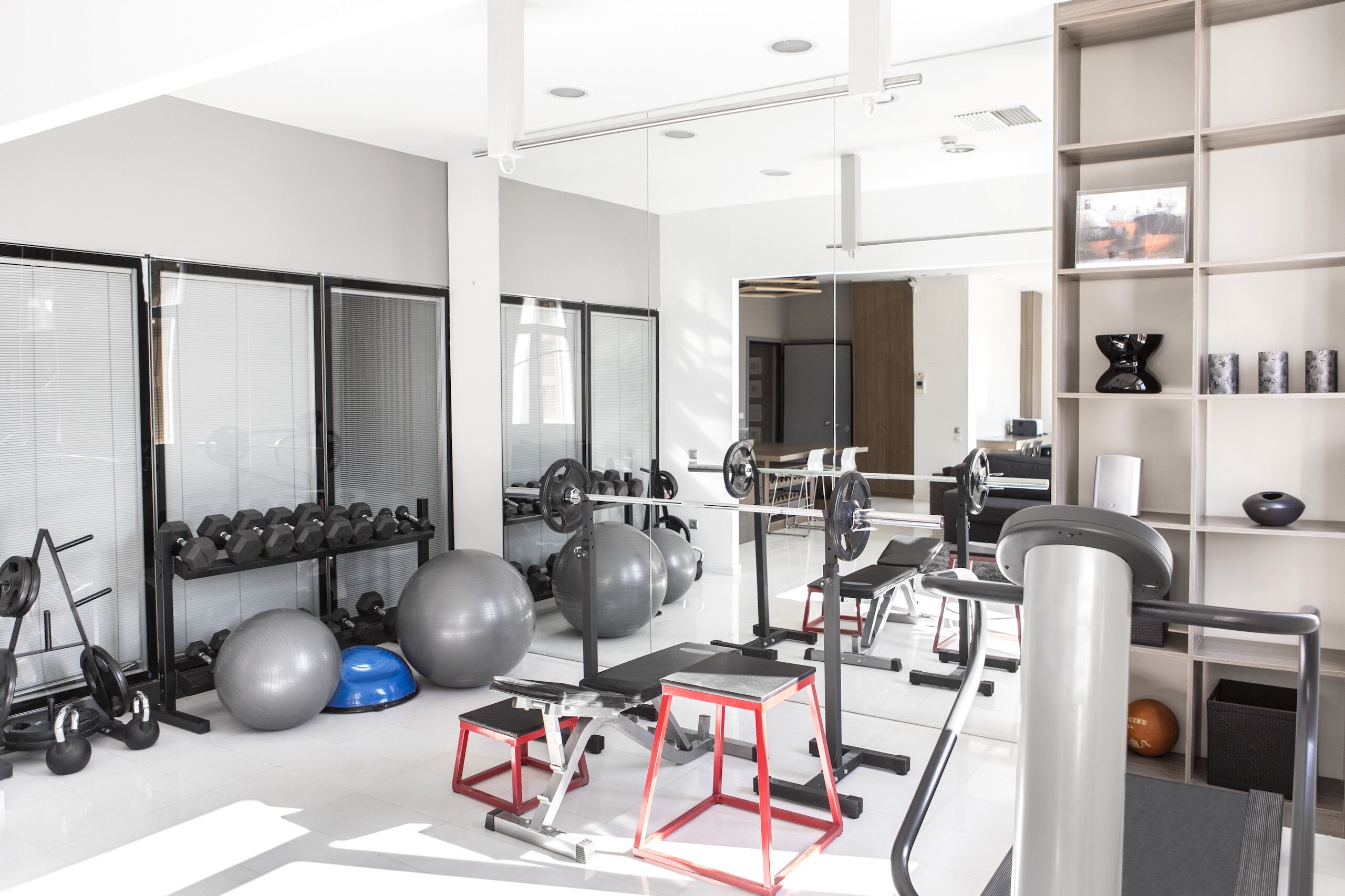 A modern gym with various exercise equipment, including dumbbells, medicine balls, and a treadmill.