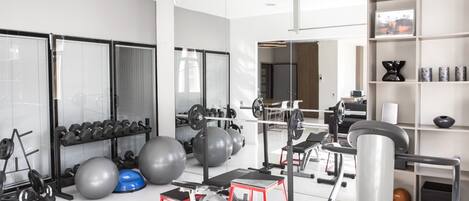 A modern gym with various exercise equipment, including dumbbells, medicine balls, and a treadmill.