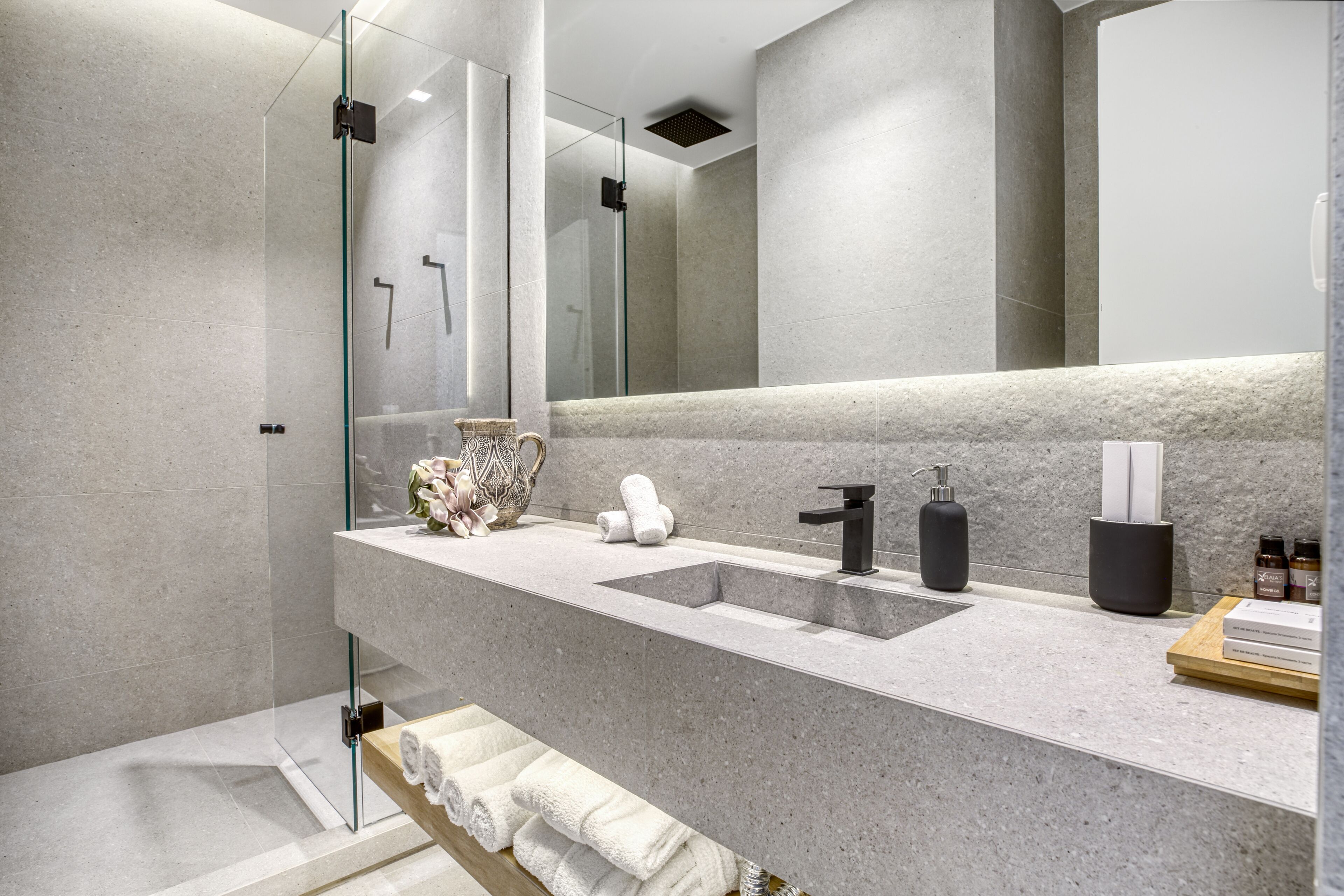 A modern bathroom with a large mirror, two sinks, and a glass shower enclosure.