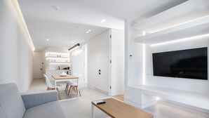 Una sala de estar moderna con un sofá gris, una mesa de centro de madera y un televisor montado.