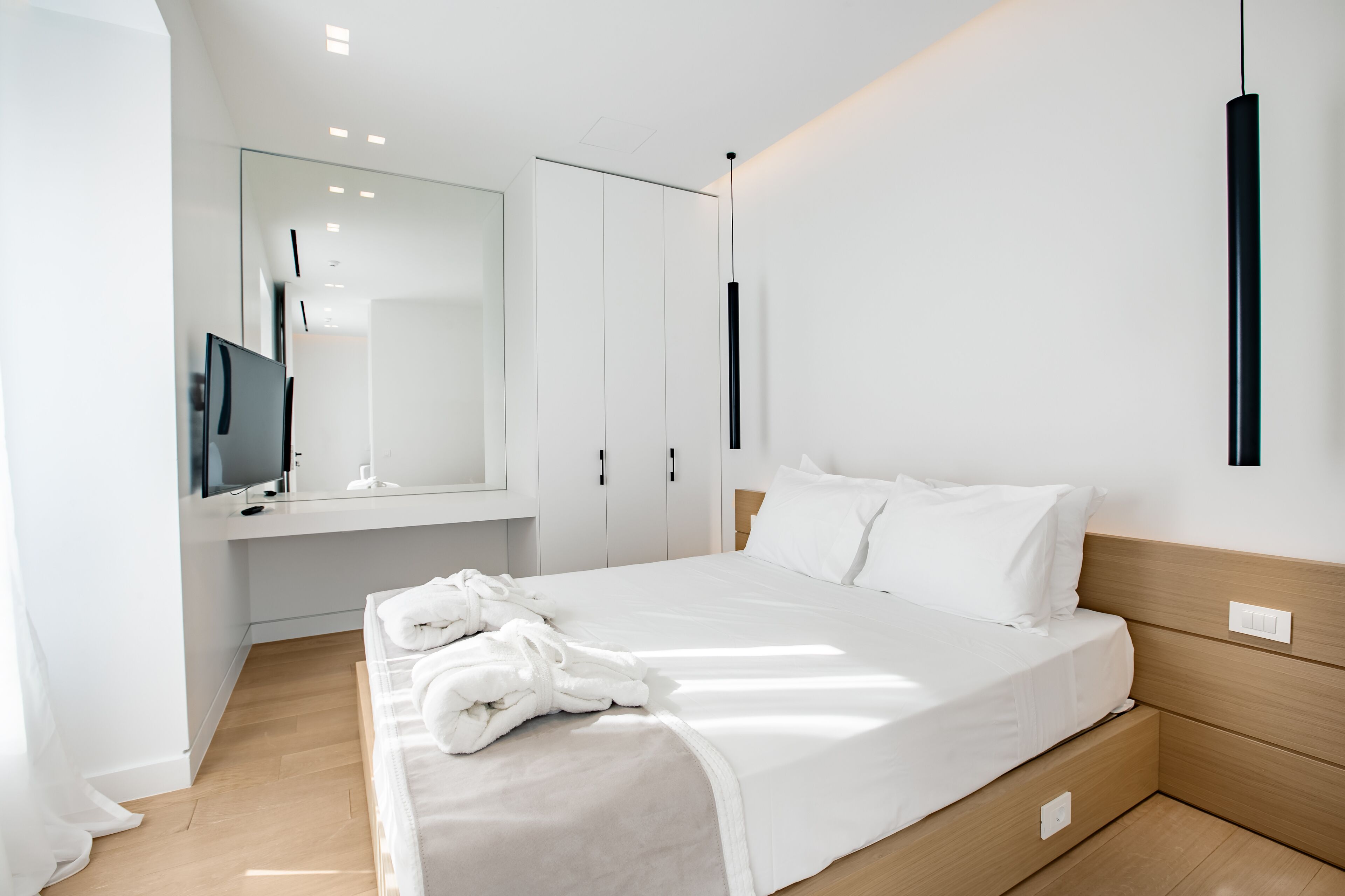 A modern bedroom with a large bed, a TV, and a wardrobe.