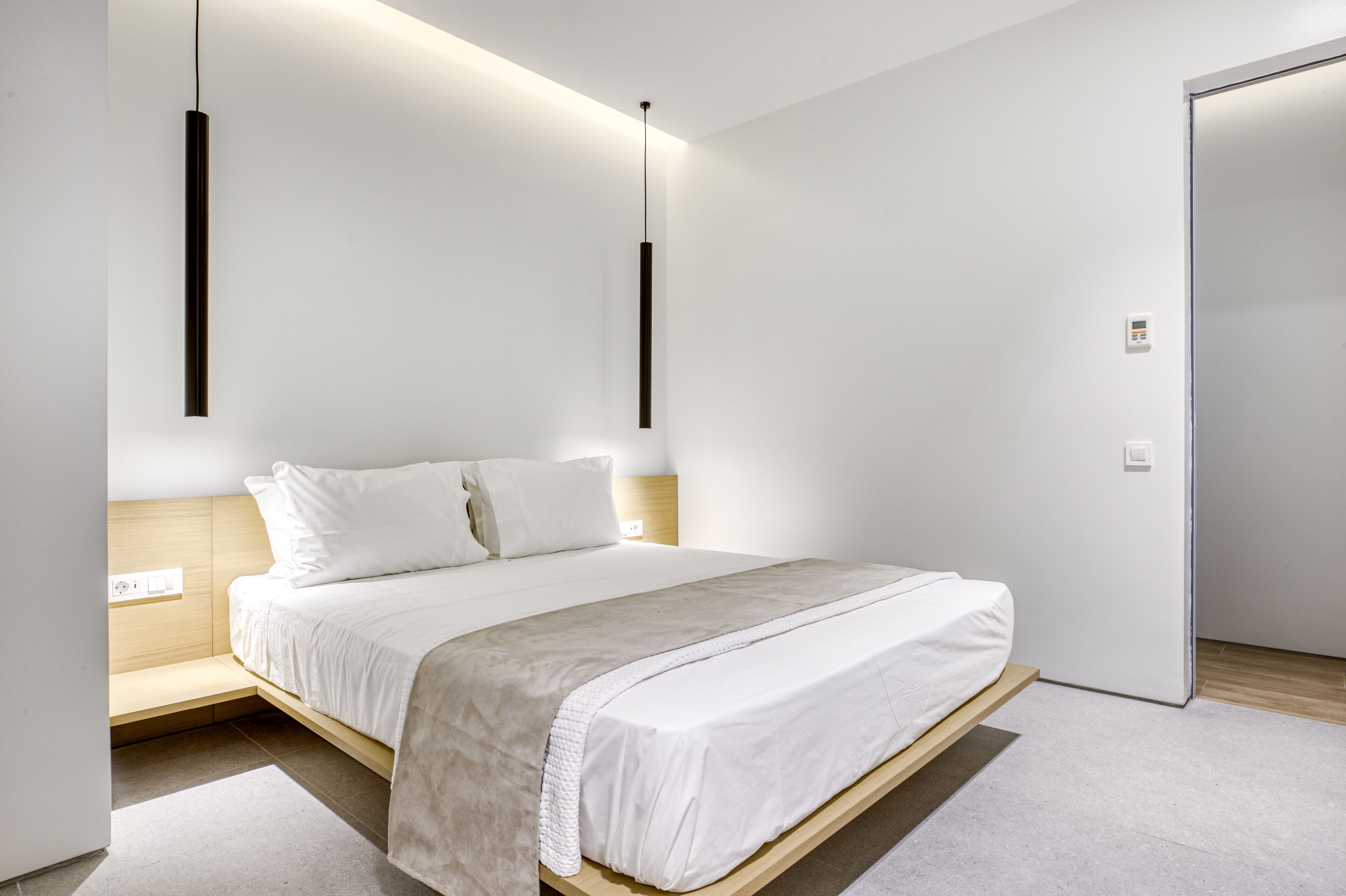 Een moderne slaapkamer met een bed, nachtkastjes en een deur.