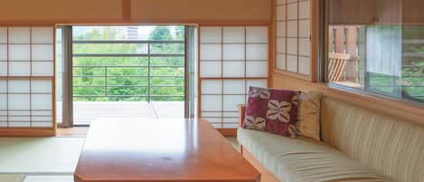 Ein traditioneller japanischer Raum mit Tatami-Böden, einem niedrigen Holztisch und einer Couch mit Kissen.