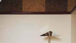 Ein hölzerner Kopfseitenverzierer, eine Lampe, ein dekoratives Metallornament und ein weißes Kopfkissen.