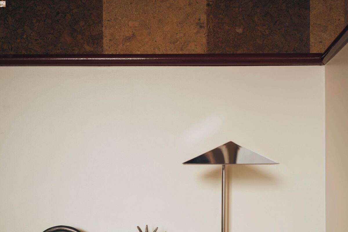 A wooden headboard with a lamp, a decorative metal piece, and a white pillow.