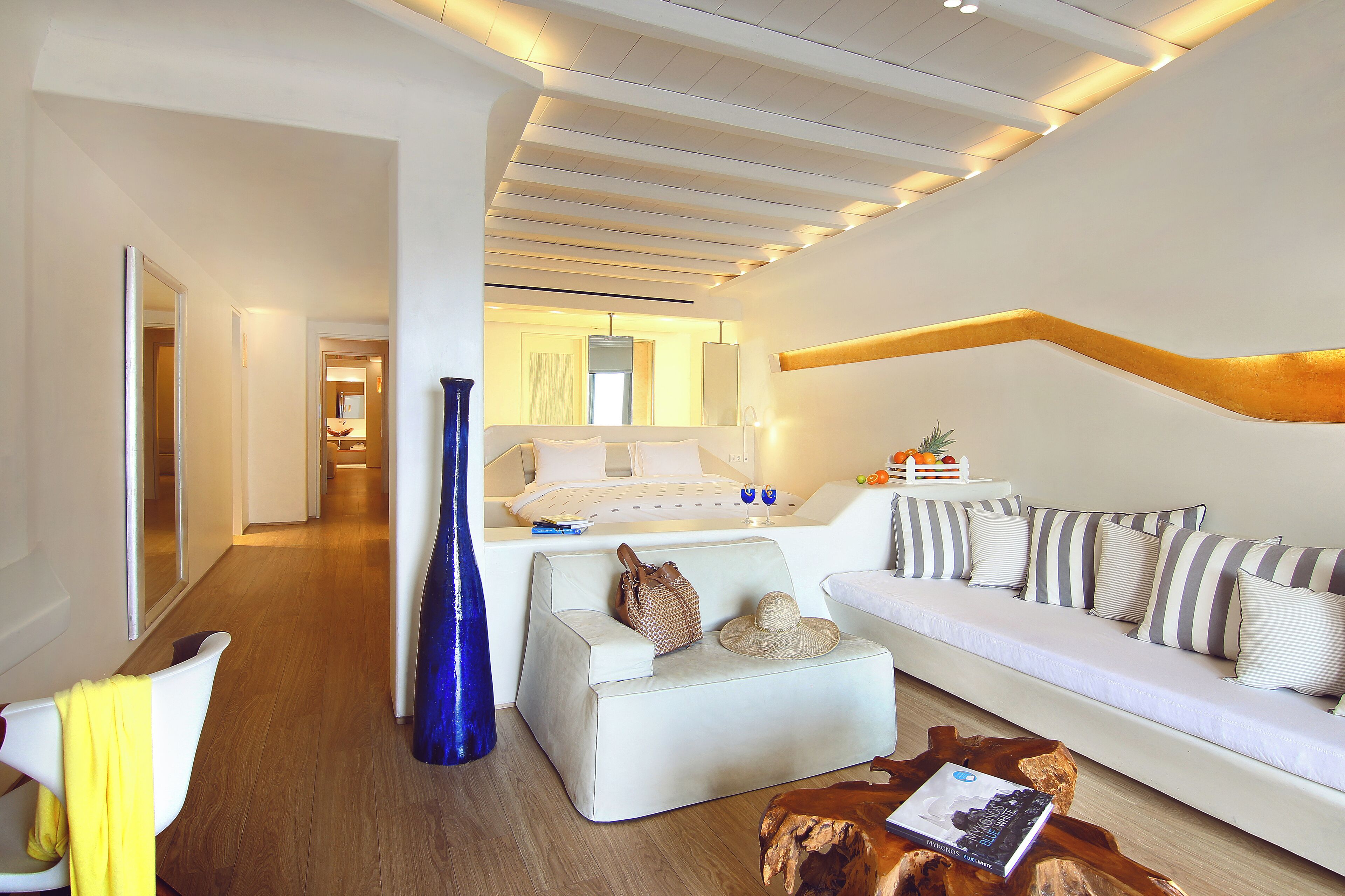 A modern living room with a sofa, ottoman, and coffee table. There is a blue vase and a wooden coffee table with a magazine.