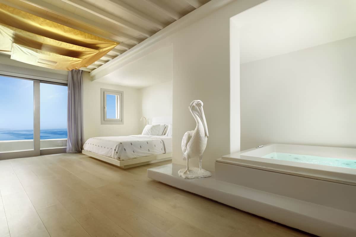 Une chambre moderne avec une grande fenêtre, un lit, une sculpture et une baignoire.