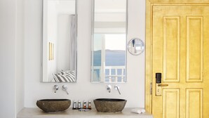 A bathroom with two stone sinks, a large mirror, and a view of the sea.