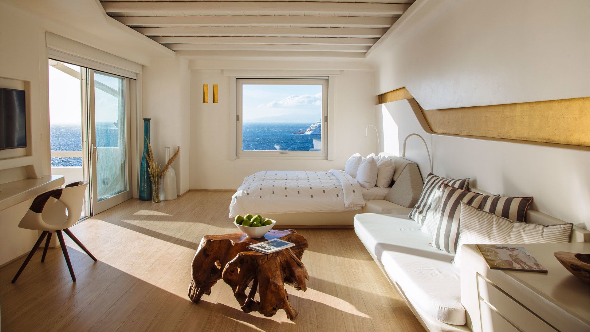 Un dormitorio moderno con un ventanal grande, una cama, un sofá y una mesa de comedor.