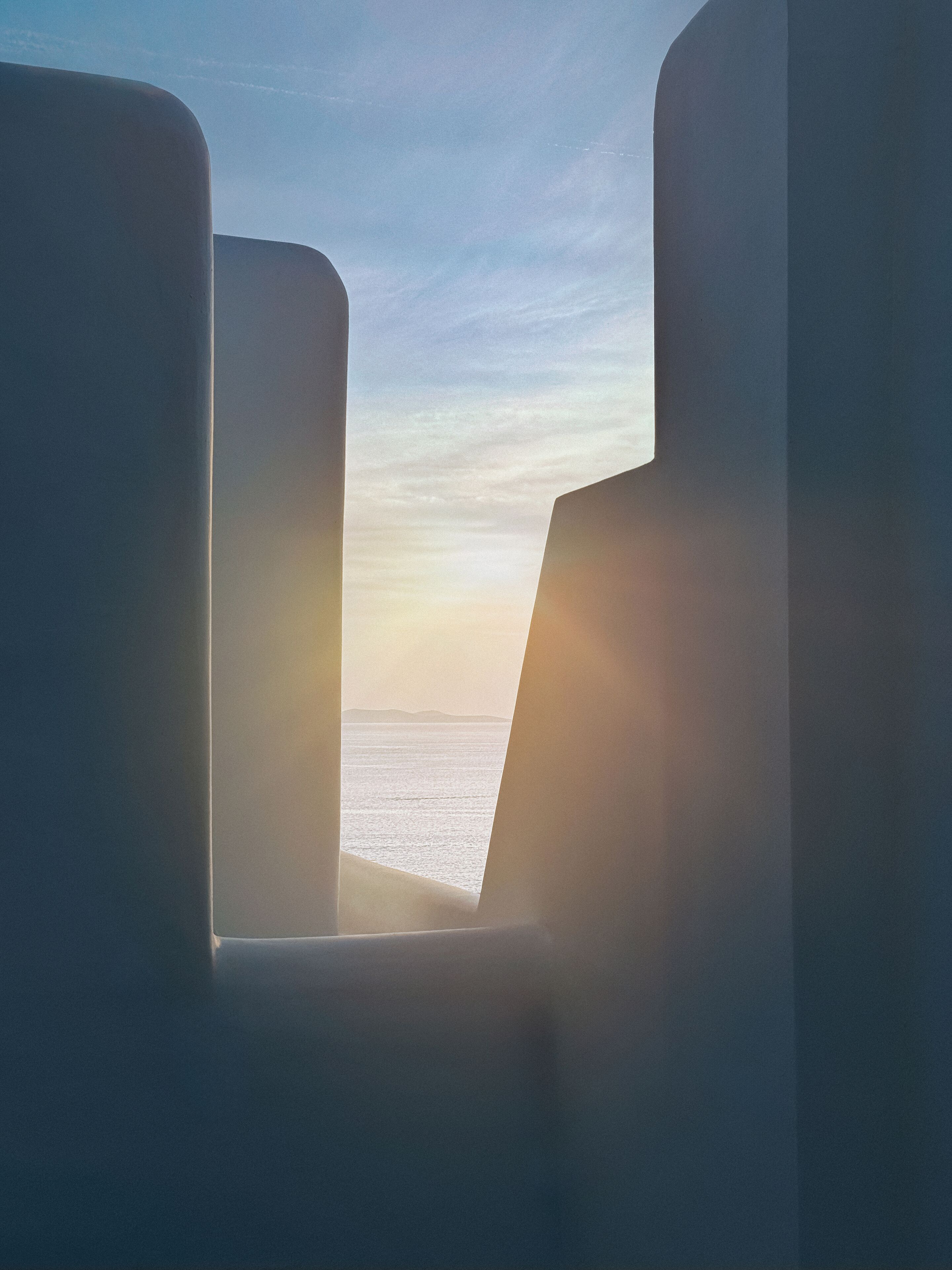 Vista desde una ventana con dos sillas mirando un cuerpo de agua y un horizonte lejano.