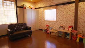 A living room with a sofa, a wooden table, and a wardrobe. - Hananoi Bed and Breakfast (Hengchun)