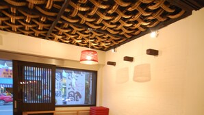 A restaurant interior with a traditional woven ceiling, wooden seating, and a view of the street outside. - Hananoi Bed and Breakfast (Hengchun)