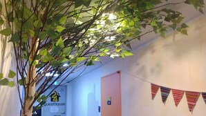 A hallway with artificial greenery, a door labeled "Guesthouse," and a patterned floor. - 24 Guesthouse Seomyun (Busan)