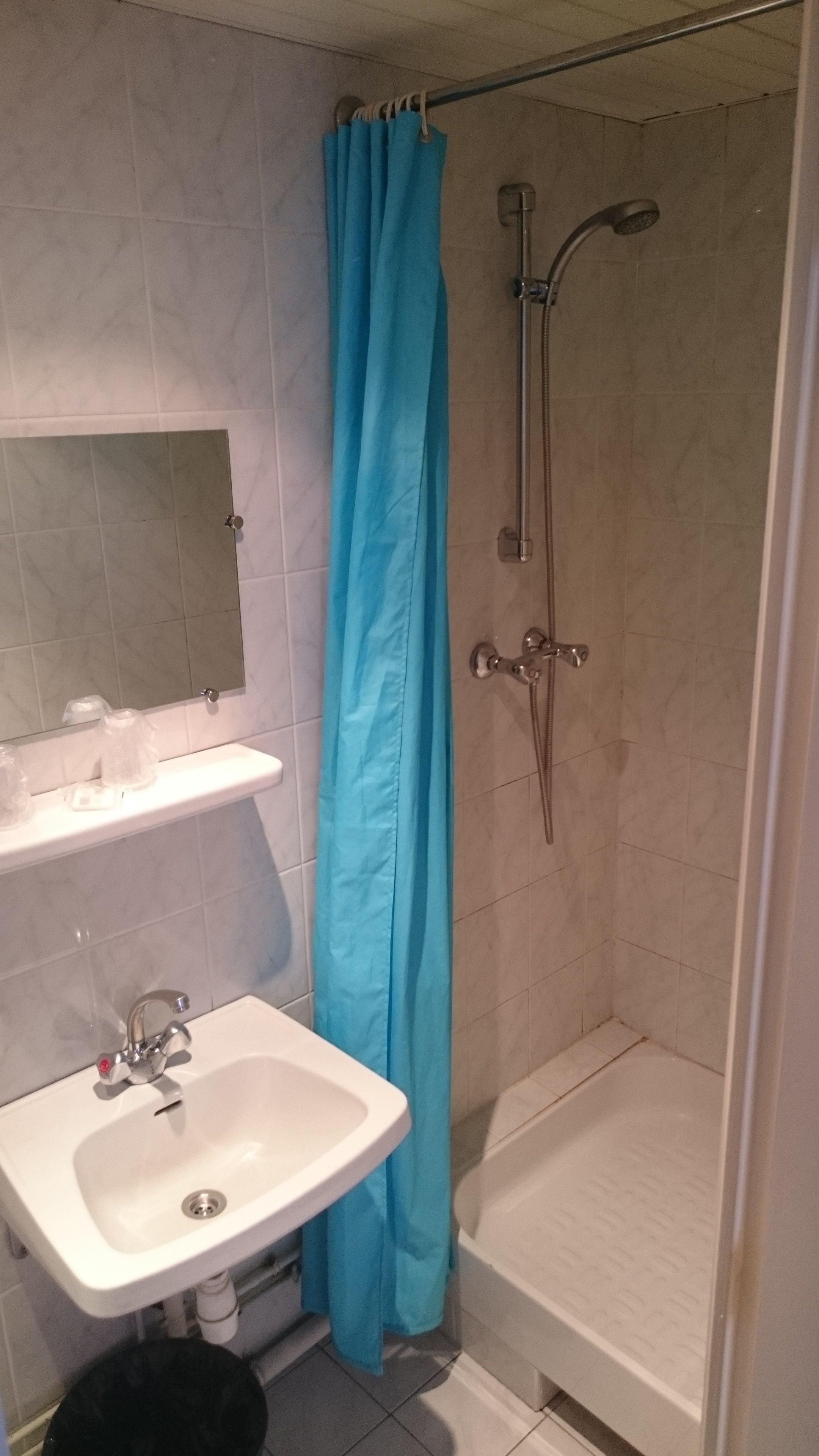 A bathroom with a shower, a sink, and a mirror.