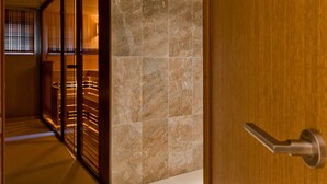 Un interior moderno con una puerta de madera, una pared con azulejos y un separador de vidrio.