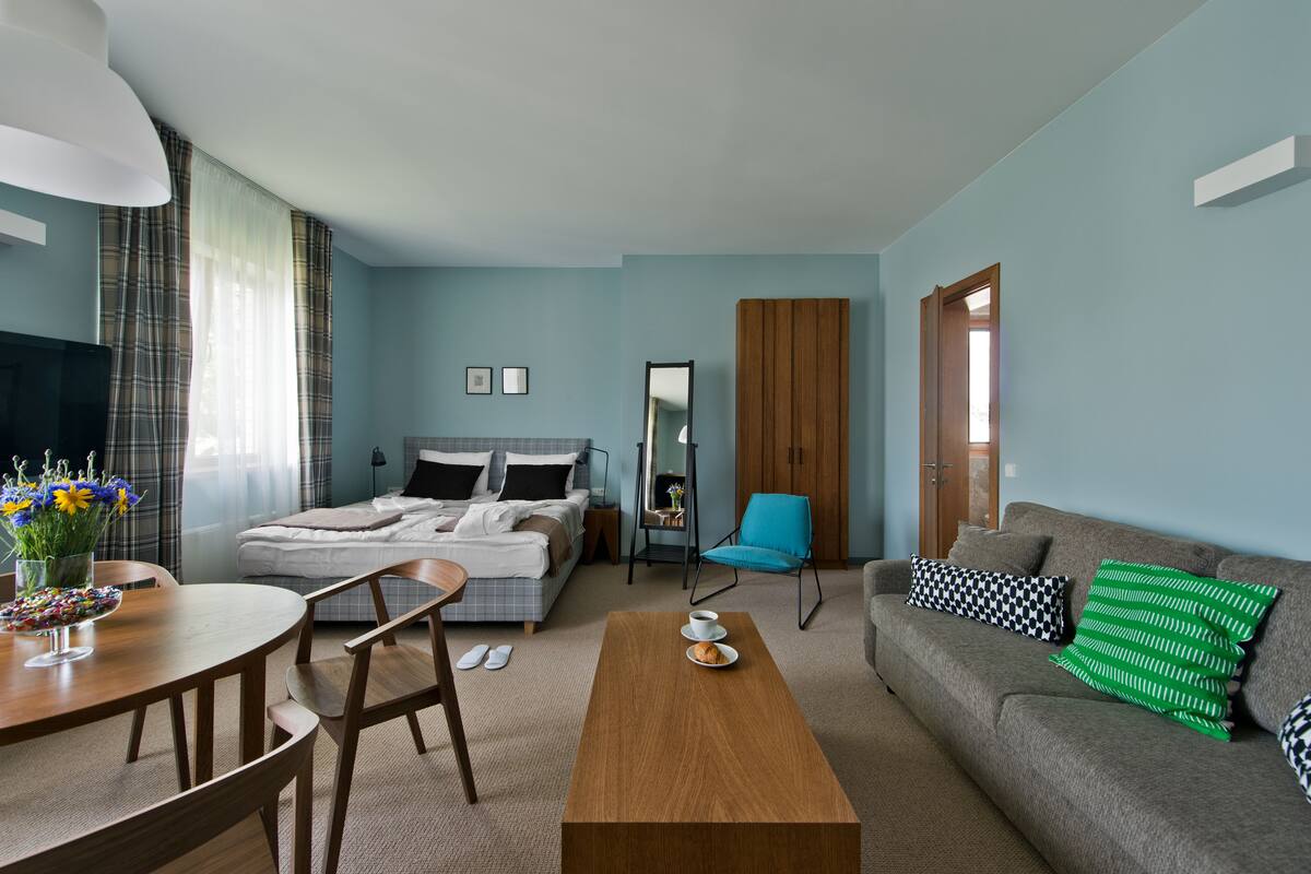 Een hotelkamer met een bed, een slaapbank, een eettafel met stoelen, een salontafel en een televisie.