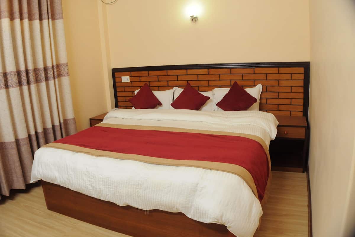 A neatly made bed with a wooden headboard, a red and white bedspread, and matching pillows.