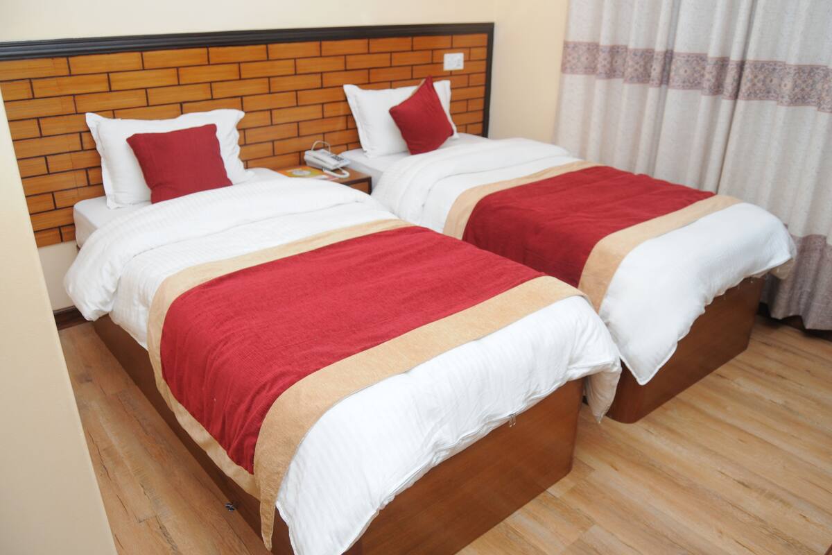 Two single beds with wooden headboards, white bedding, and red accents.