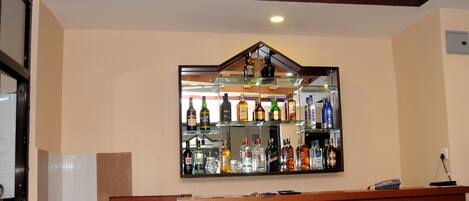 A bar area with a wooden ceiling and a mirrored wall displaying various liquor bottles.
