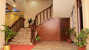 A staircase with wooden railings leading to a door, surrounded by potted plants. - Hotel Bagmati (Kathmandu)