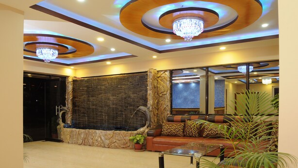 A lobby with a stone wall, a wooden bench, and a chandelier. - Hotel Bagmati (Kathmandu)
