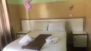 Una cama bien hecha con ropa de cama blanca y marrón, una toalla blanca y un dosel rosa.