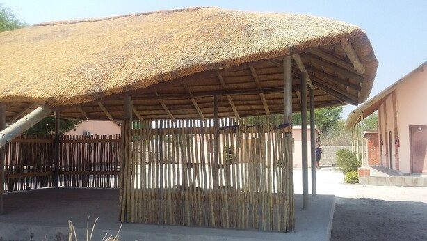 Un espacio al aire libre cubierto con techo de paja y valla de bambú.