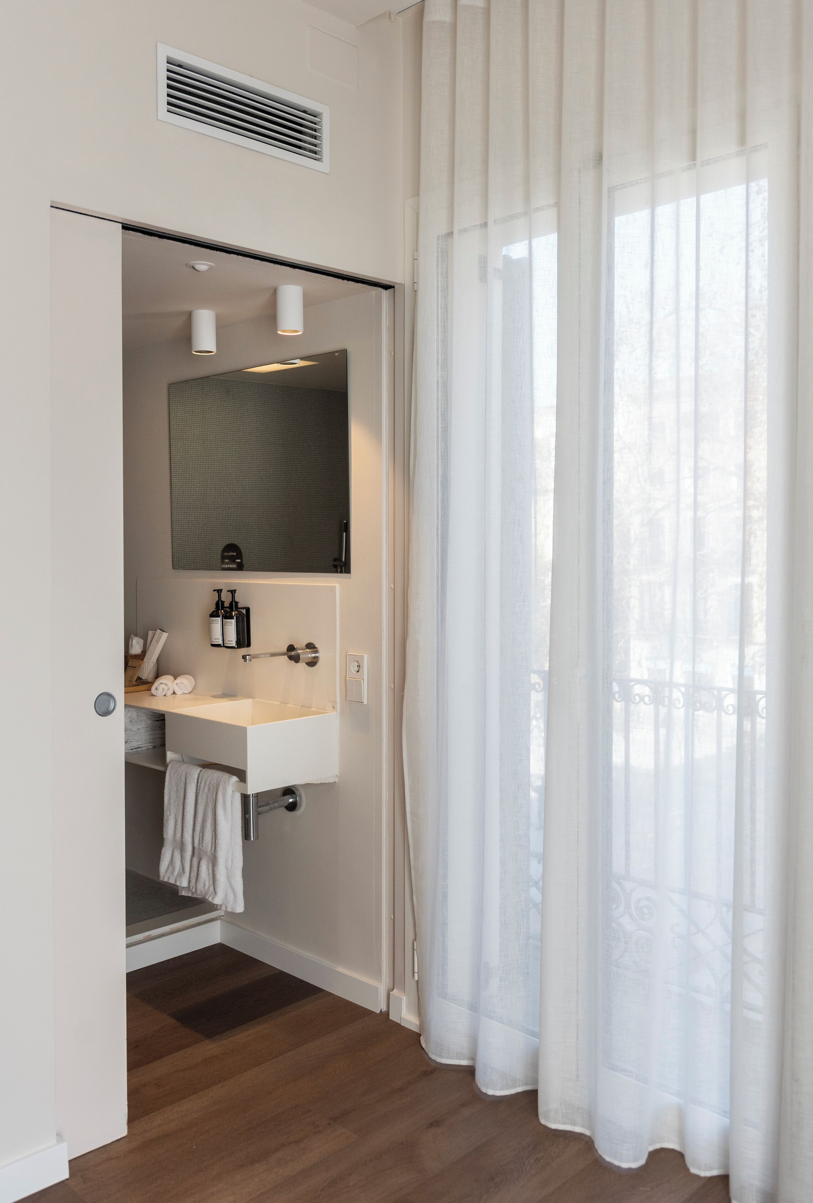 A bathroom with a white sink, mirror, and towel rack.
