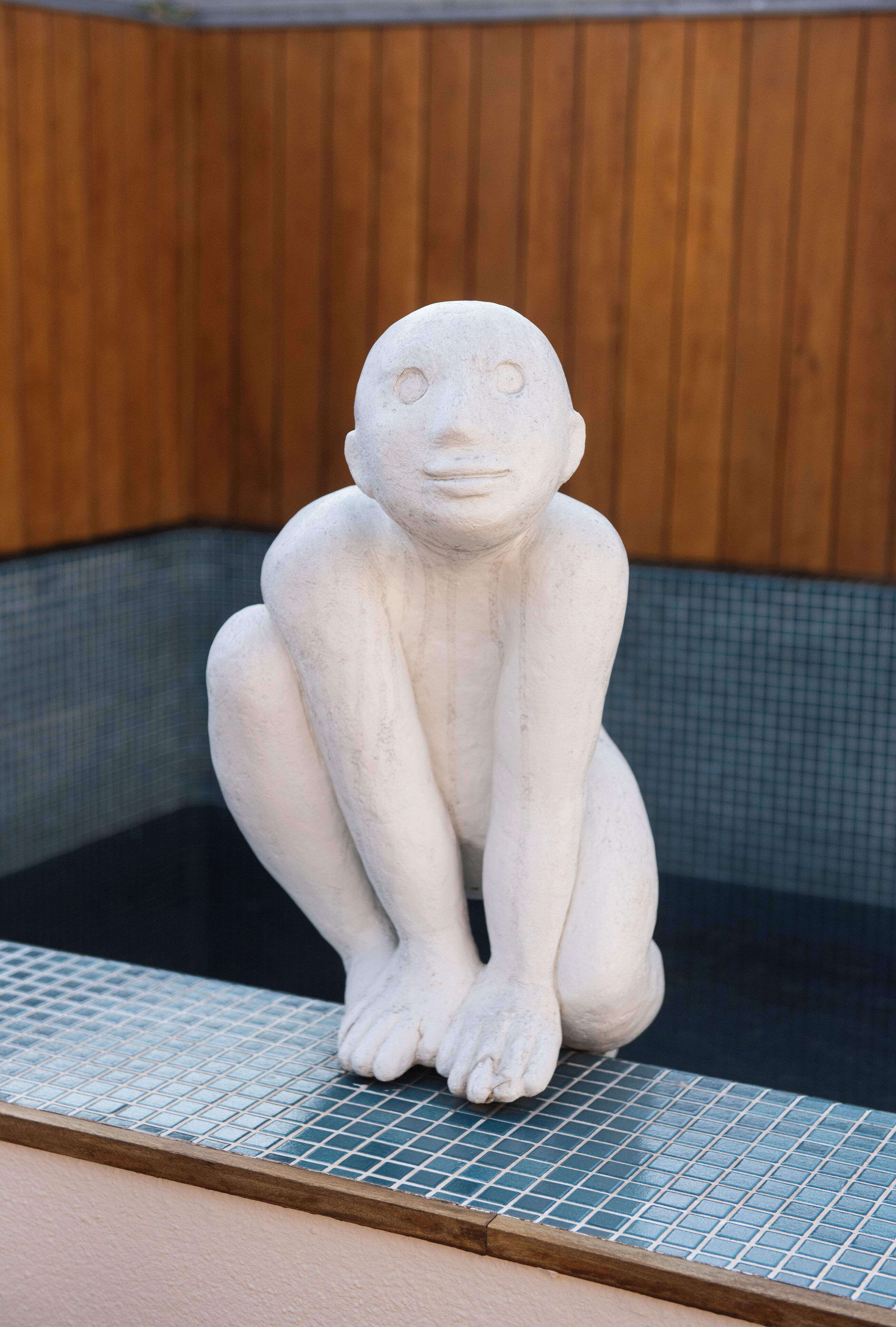 Una estatua de piedra de una figura sentada en un área con baldosas.