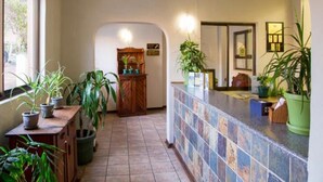 Een hotel lobby met een betegelde vloer, een receptiebalie en verschillende potplanten.