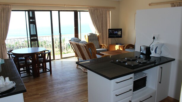 Een moderne keuken met een eethoek, een flatscreen televisie en uitzicht op de oceaan.