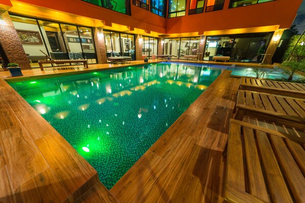 Una piscina al aire libre, sombrillas, sillones reclinables de piscina