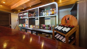 A bar area with wooden shelves stocked with various bottles and glasses. - Thongtara House Boutique Residence (Samut Prakan)