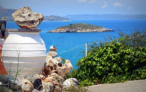 Un paisaje costero con un jarrón blanco grande, rocas y una cerca con vista al mar.
