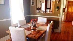 Une table à manger avec quatre chaises, une bouteille et deux verres à vin.