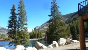 A lakeside view with a wooden deck and a mountain backdrop. - Elk Creek Lodge 3 Bedroom Holiday Home By Pinon Vacation Rentals (Salida)
