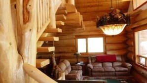 A log cabin interior with a staircase, a sofa, and a chandelier. - Elk Creek Lodge 3 Bedroom Holiday Home By Pinon Vacation Rentals (Salida)