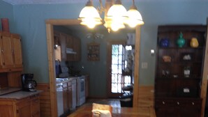 A wooden dining table with a bench, a coffee maker, and a cabinet in a kitchen area. - Forest Creek Cabin 3 Bedroom Holiday Home By Pinon Vacation Rentals (Monarch)