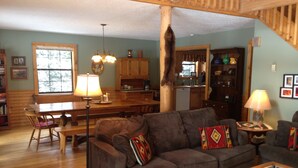 A cozy living room with a sofa, a coffee table, and a dining area with a table and chairs. - Forest Creek Cabin 3 Bedroom Holiday Home By Pinon Vacation Rentals (Monarch)