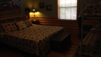 A room with a bed, a bench, a lamp, and a window.