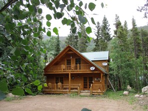 A two-story log cabin with a balcony, surrounded by forest. - Forest Creek Cabin 3 Bedroom Holiday Home By Pinon Vacation Rentals (Monarch)