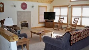 Een gezellige woonkamer met een open haard, een televisie en comfortabele zitplaatsen.