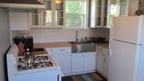 Une cuisine avec des armoires blanches, une cuisinière à gaz, un évier et un réfrigérateur.
