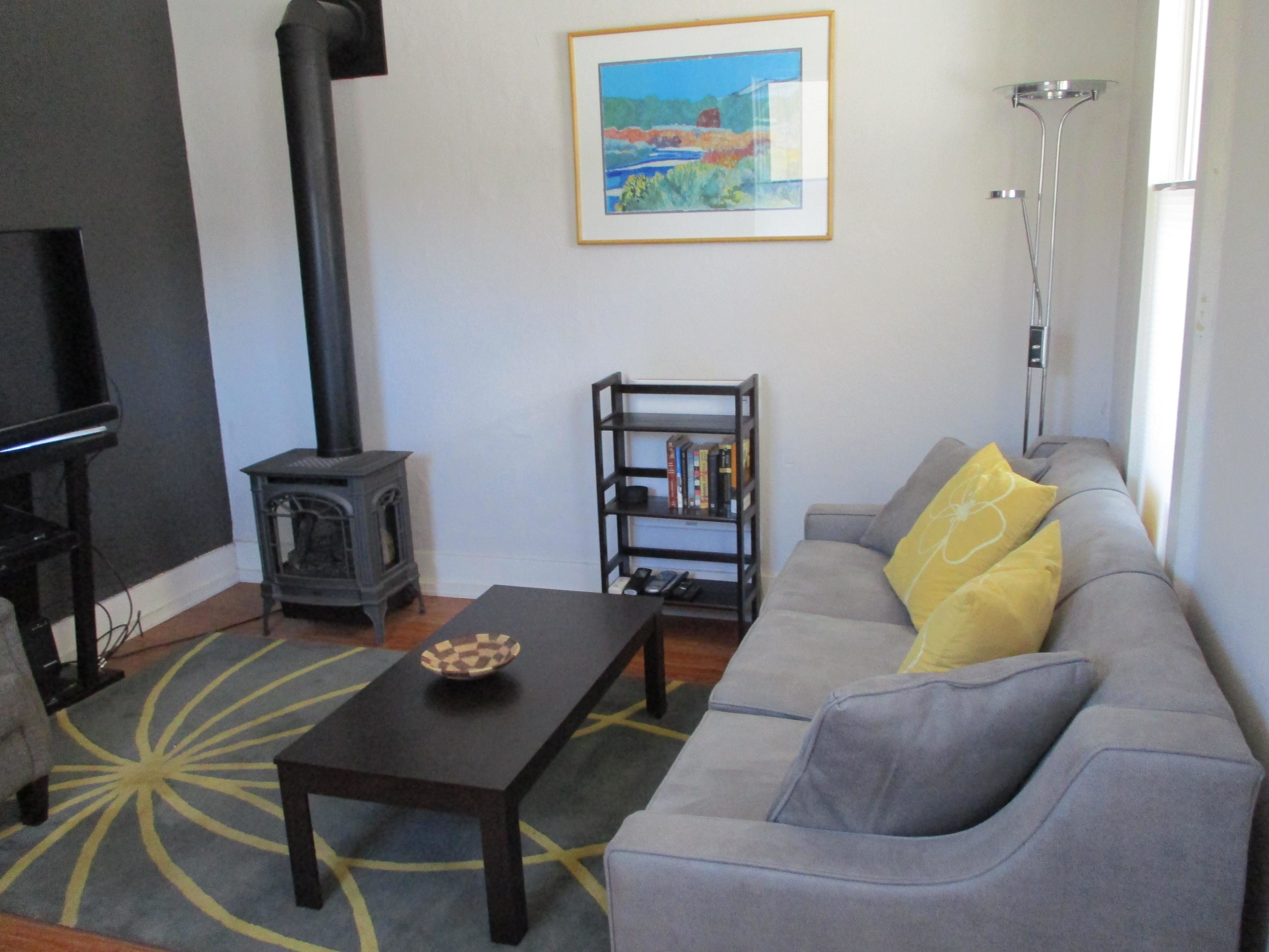 A living room with a sofa, a coffee table, a bookshelf, a fireplace, and a painting on the wall.