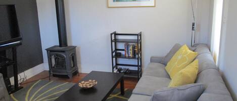 A living room with a sofa, a coffee table, a bookshelf, a fireplace, and a painting on the wall.