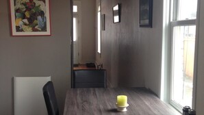 Un espace repas comprenant une table en bois, des chaises, des luminaires suspendus et des œuvres d’art accrochées aux murs.