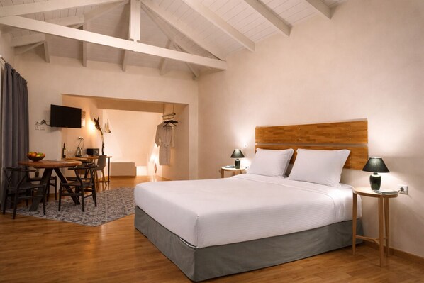 Una habitación de hotel con una cama grande, un escritorio con silla, un televisor y techo de madera.