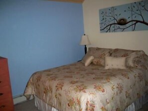 Une chambre à coucher avec un lit, une commode et un tableau au mur.