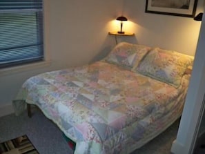 A bedroom with a bed, a nightstand with a lamp, a window with blinds, and a framed picture on the wall. - Mountain High 2 Bedroom Holiday Home By Pinon Vacation Rentals (Monarch)